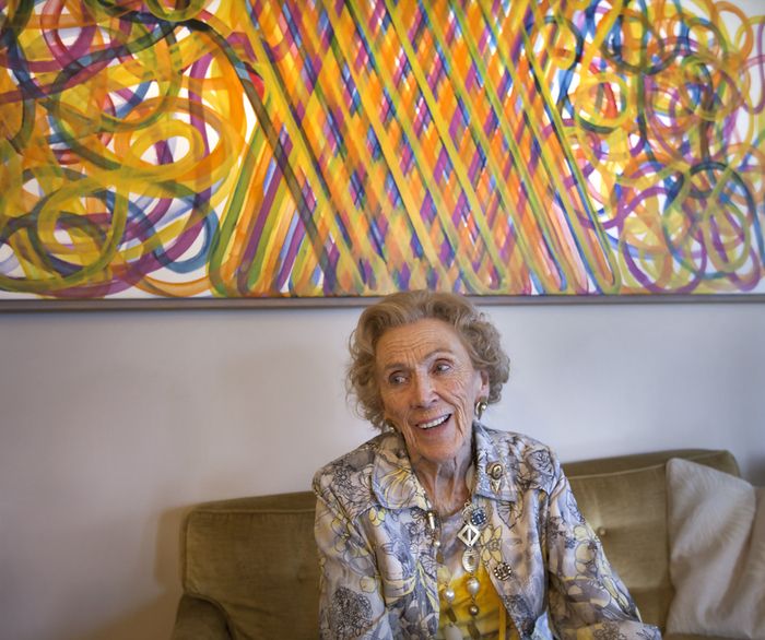 Jacqui Shumiatcher at home with a painting by Ted Godwin